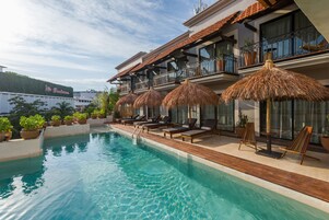 Una piscina al aire libre, sombrillas, sillones reclinables de piscina