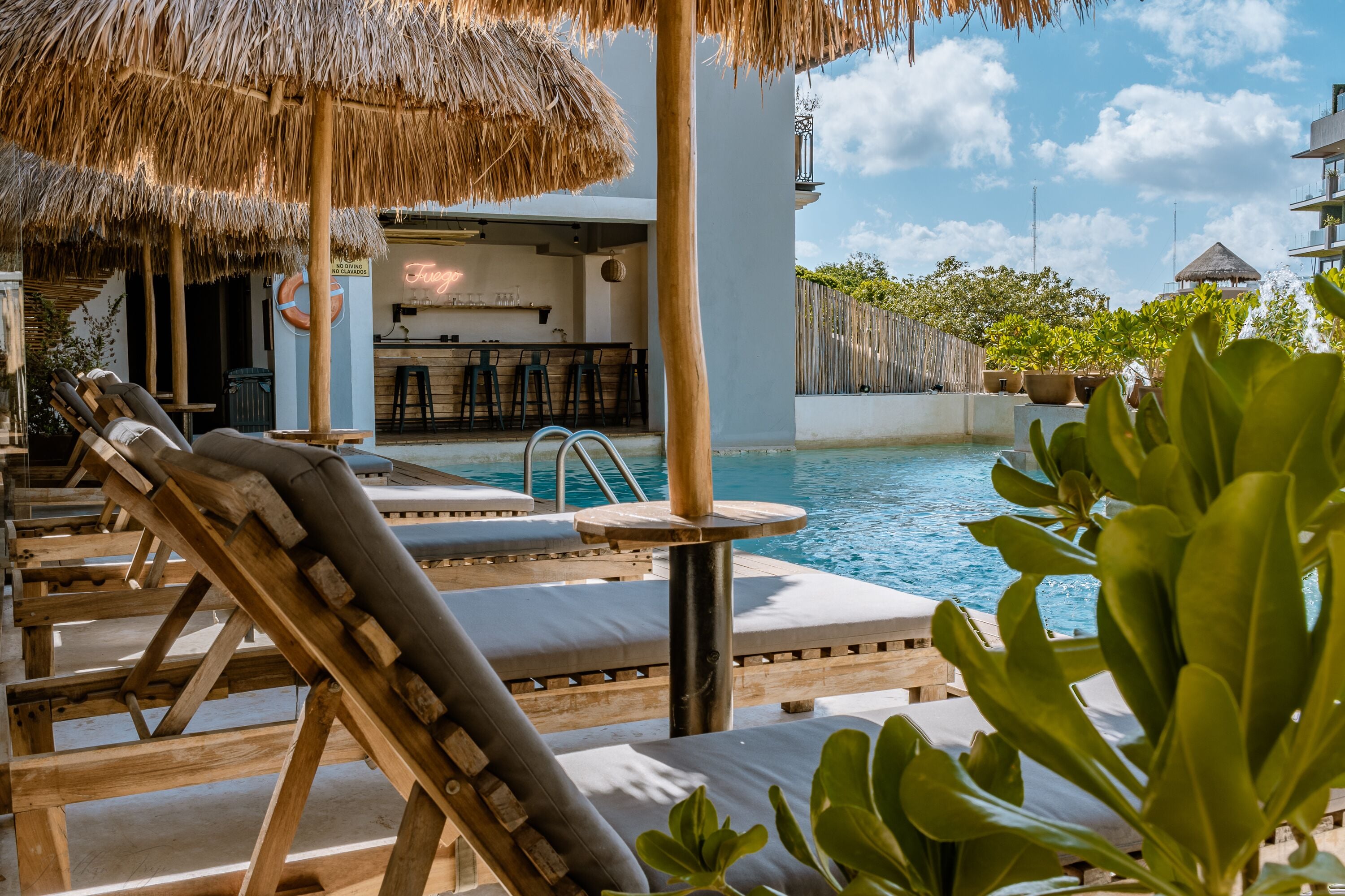 A poolside area with lounge chairs, a bar, and a thatched umbrella.