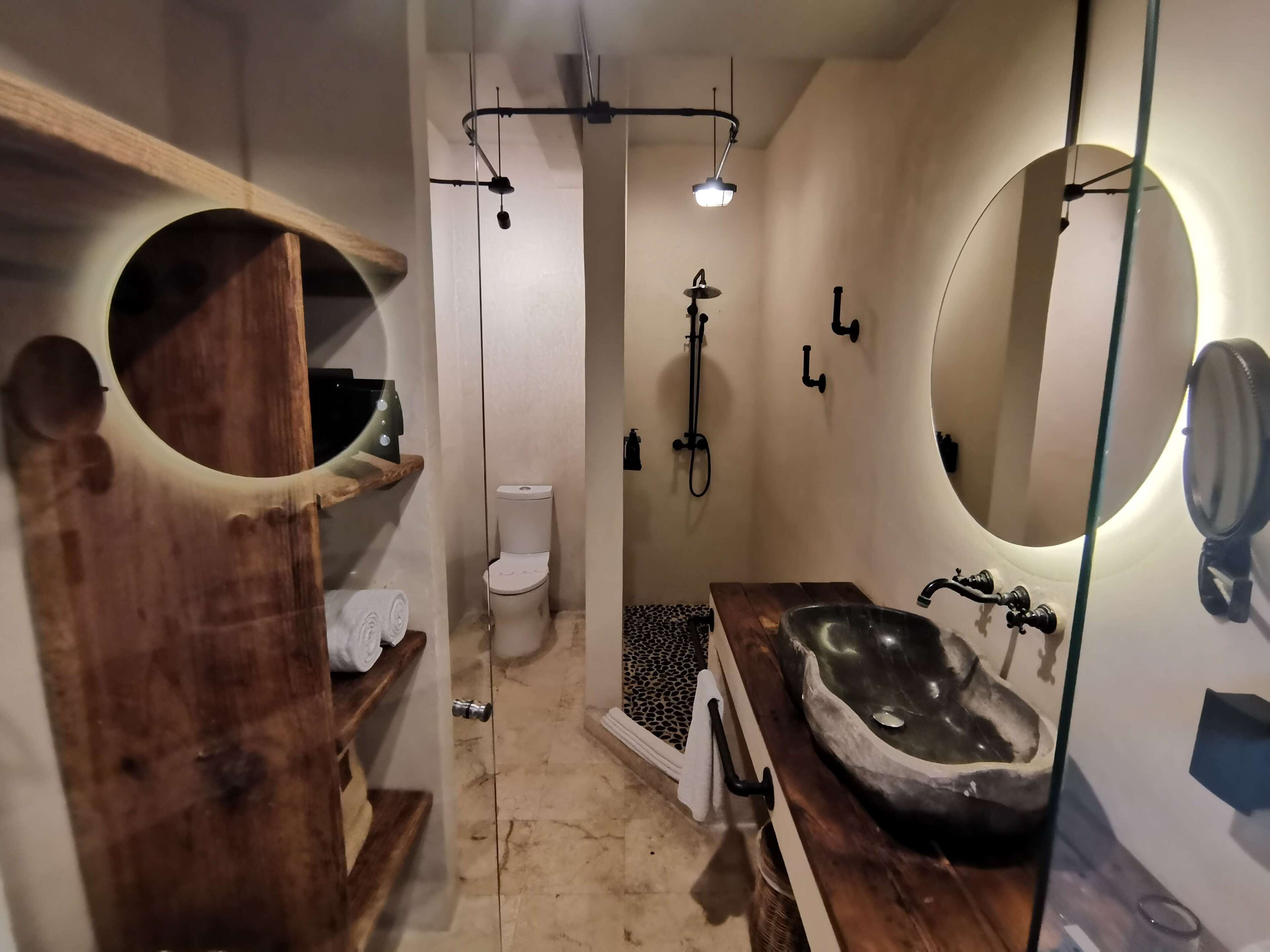 Ein modernes Badezimmer mit einem Holzkonsolenunterschrank, einem großen Waschbecken, einer Toilette und einer Dusche.