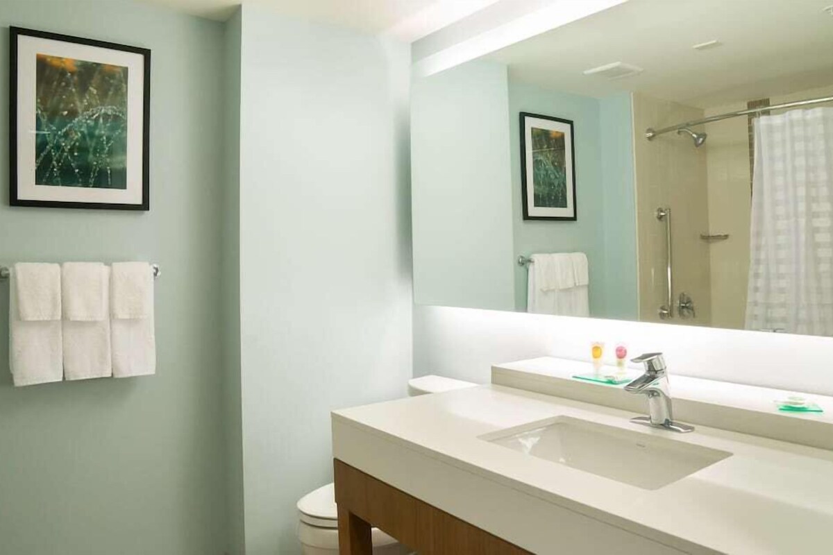 A bathroom with a large mirror, a sink, and a shower.