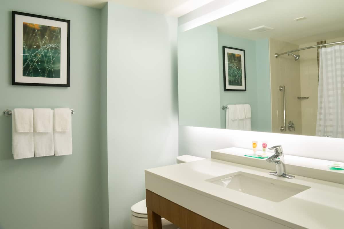 Een badkamer met een wit wastafel, een grote spiegel en een douche met een glazen deur.