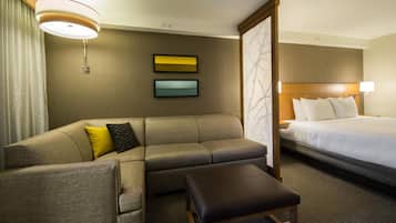 A hotel room with a sofa, a bed, a desk, and a chair.