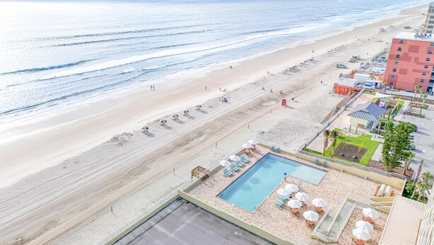 A beachside hotel with a swimming pool, beach umbrellas, and a view of the ocean. - Hyatt Place Daytona Beach - Oceanfront (Daytona Beach Shores)