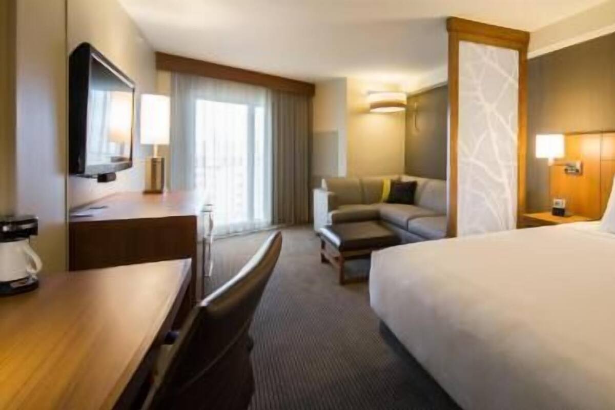 Een hotelkamer met een bed, een bureau, een stoel, een bank, een televisie en een koffiezetapparaat.
