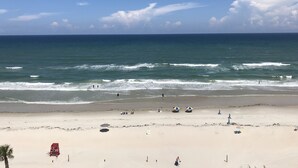 A beach with a lifeguard tower, umbrellas, and a clear view of the ocean. - Hyatt Place Daytona Beach - Oceanfront (Daytona Beach Shores)