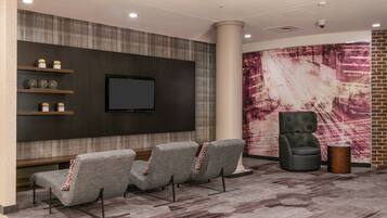 A lobby with a seating area, a flat-screen TV mounted on the wall, and a large abstract painting.