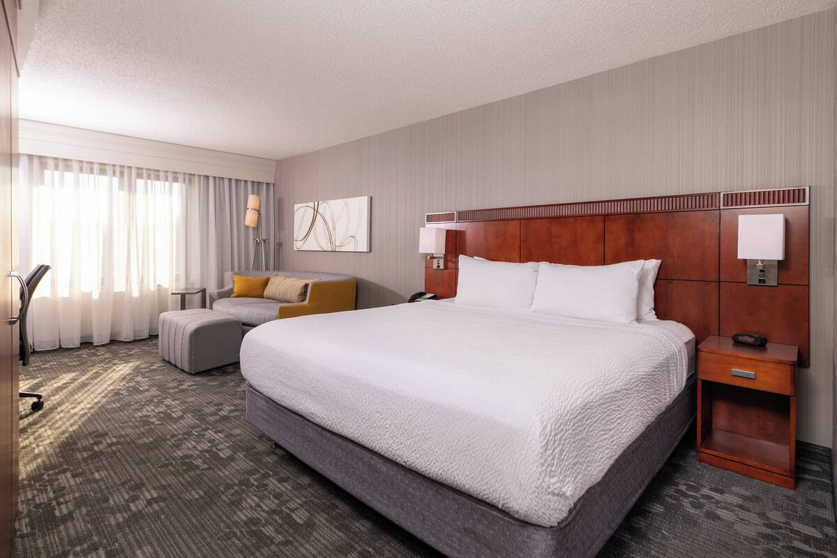 Een hotelkamer met een groot bed, een bank, een bureau en een lamp.