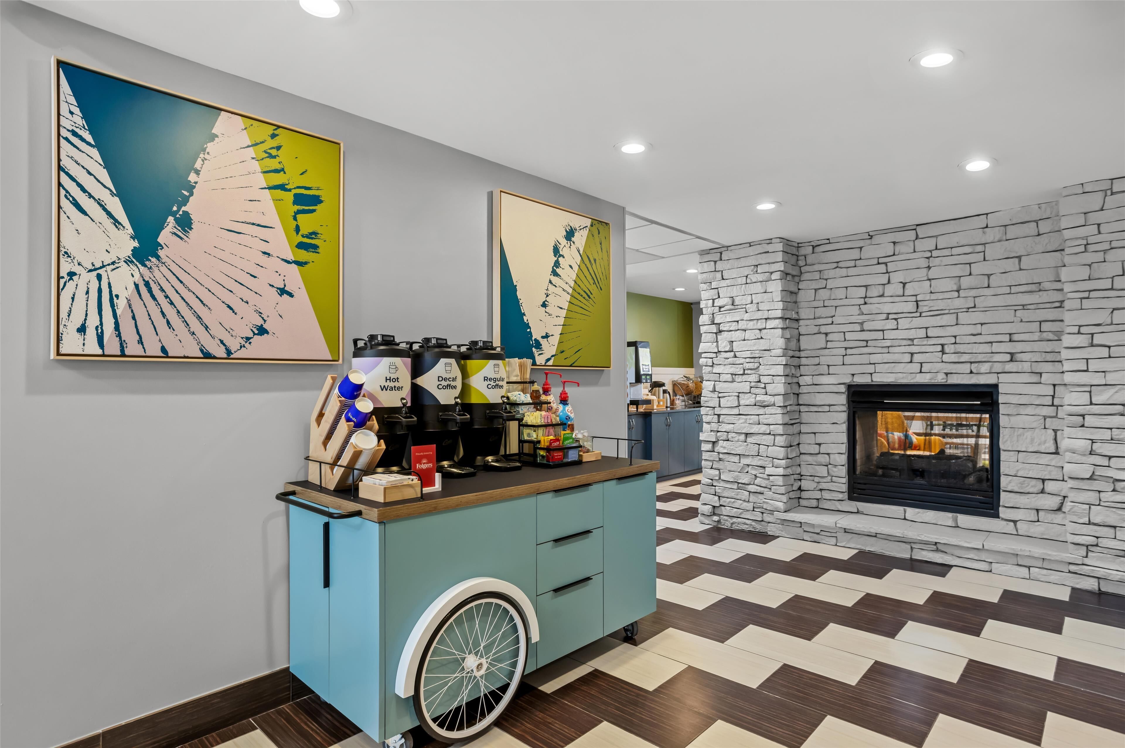 Un intérieur moderne agrémenté d’un coin café, d’œuvres d’art, d’un mur en pierre et d’une cheminée.
