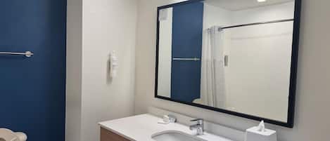 Un baño con lavamanos blanco, un espejo, toallero y un inodoro.
