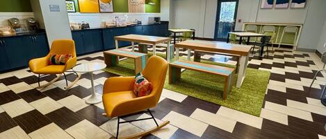 A modern hotel lobby with checkered flooring, rocking chairs, and a central dining area with tables and chairs.