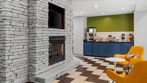 Une cuisine moderne avec une cheminée en pierre, des armoires bleues et un carrelage à motifs.