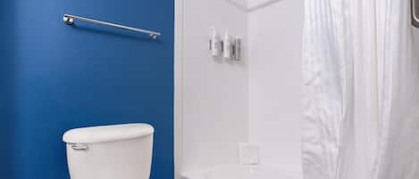 Een badkamer met een wit toilet, een bad en een douchegordijn.