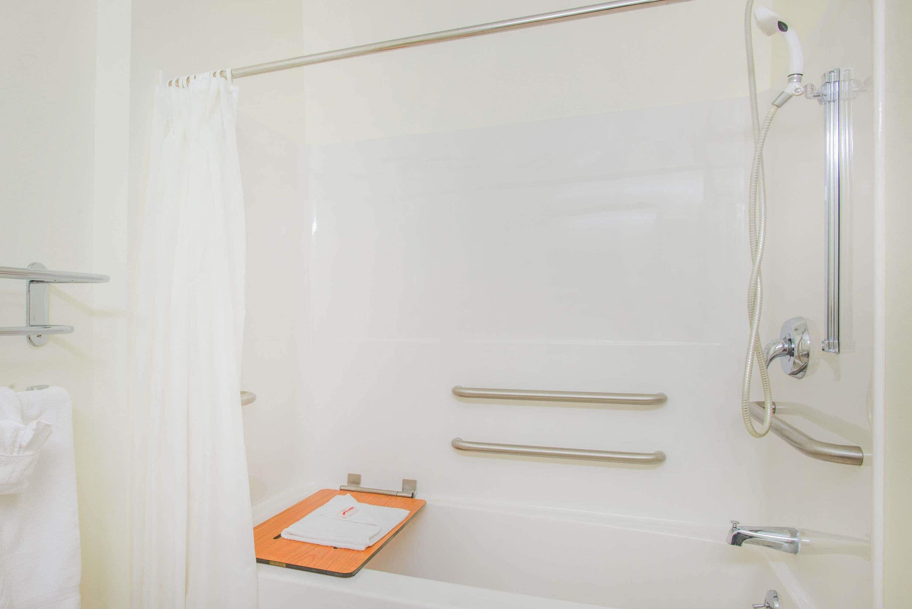 Un baño con ducha, toallero y un portapapeles en el suelo.