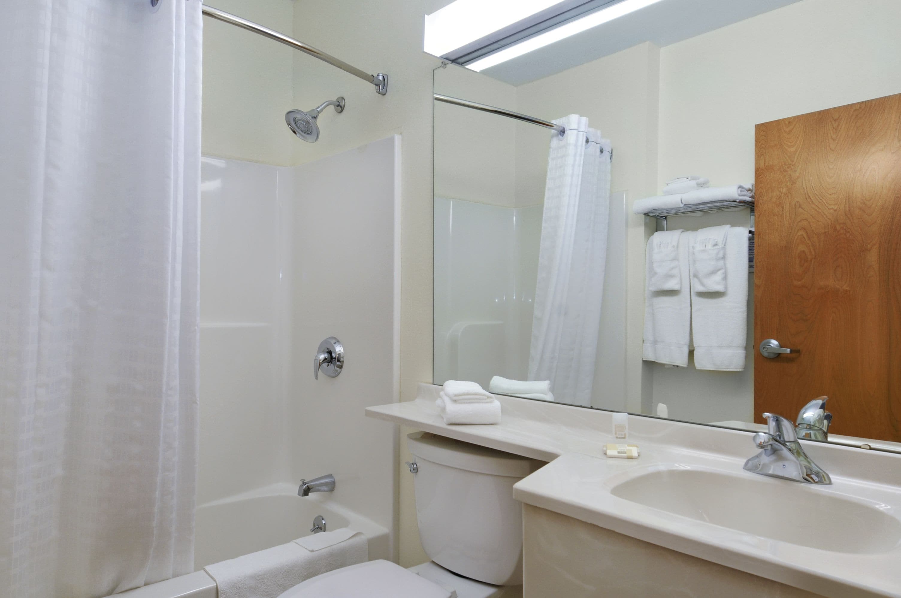 Ein Badezimmer mit einer Badewanne, Toilette, Waschbecken und einem Spiegel.