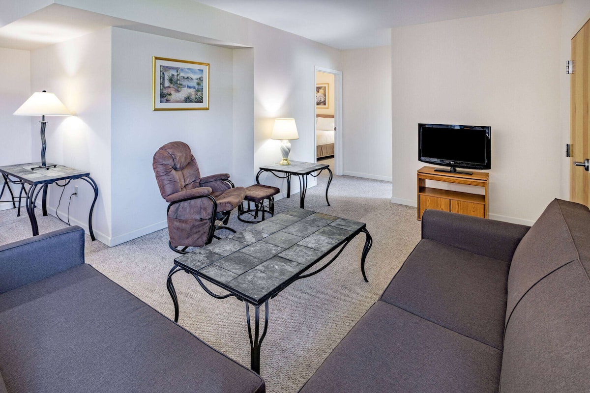 A modern living room with a sofa, armchair, coffee table, and TV stand.