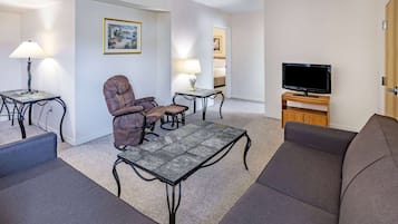 A modern living room with a sofa, armchair, coffee table, and TV stand.