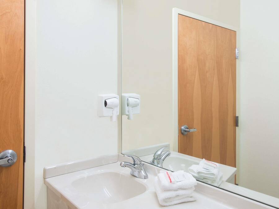 A bathroom with a sink, mirror, and towel dispenser.