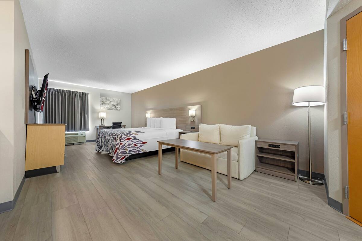 Une chambre d’hôtel comprenant un lit, un canapé, un bureau, une lampe, une télévision et une armoire.