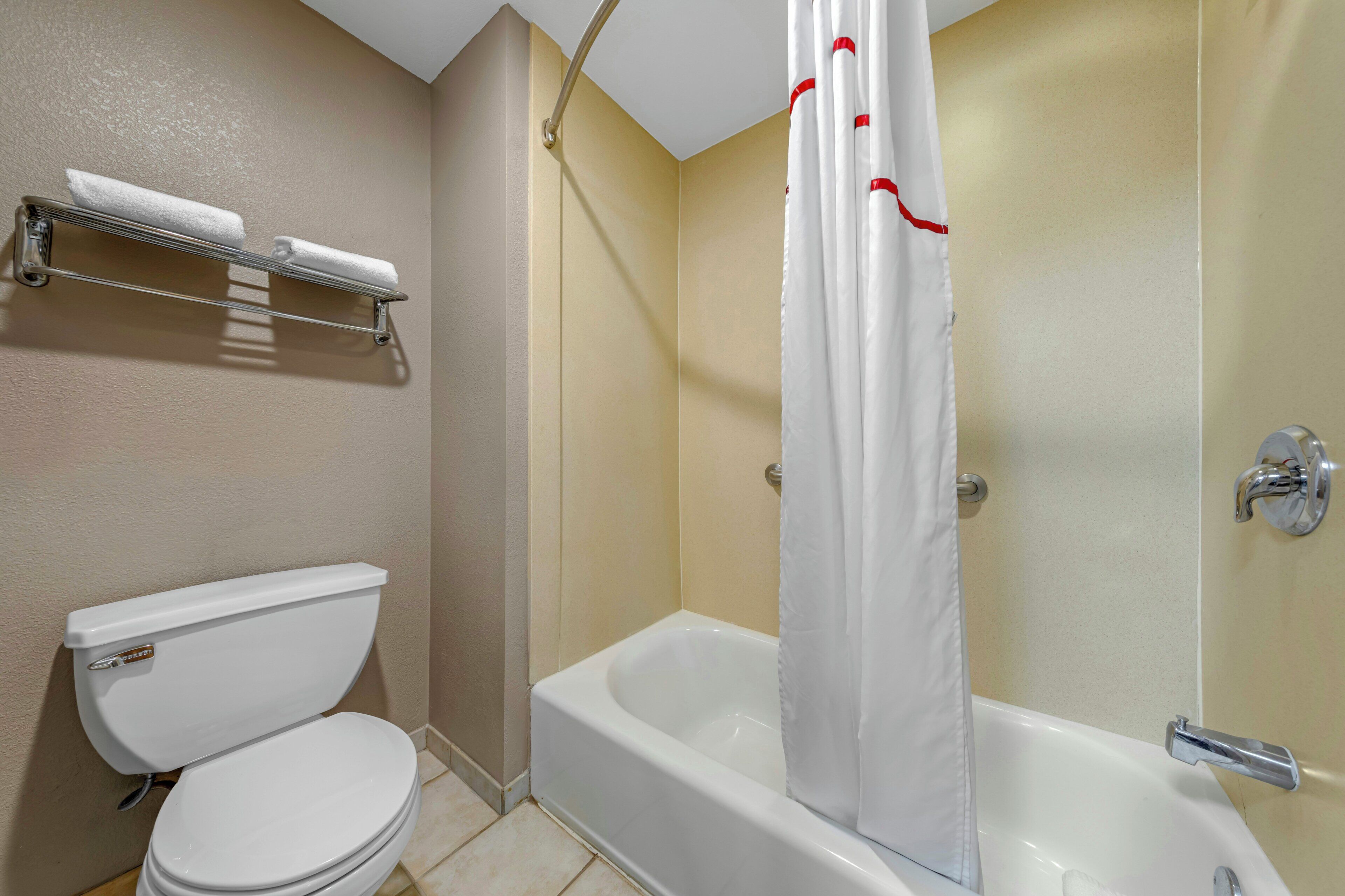 Un baño con inodoro, bañera y cortina de ducha.