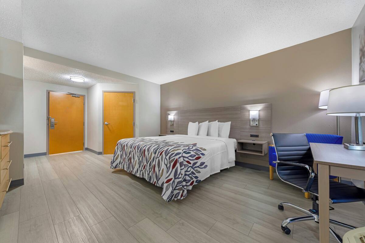 Une chambre d’hôtel équipée d’un lit, d’un bureau, d’une chaise et de deux portes.
