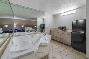 A modern bathroom with a large bathtub, a mirror, a sink, a refrigerator, and a microwave. - Red Roof Inn & Suites Philadelphia - Bellmawr (Bellmawr)