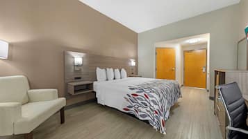 Ein Hotelzimmer mit Bett, Stuhl, Schreibtisch und Spiegel.