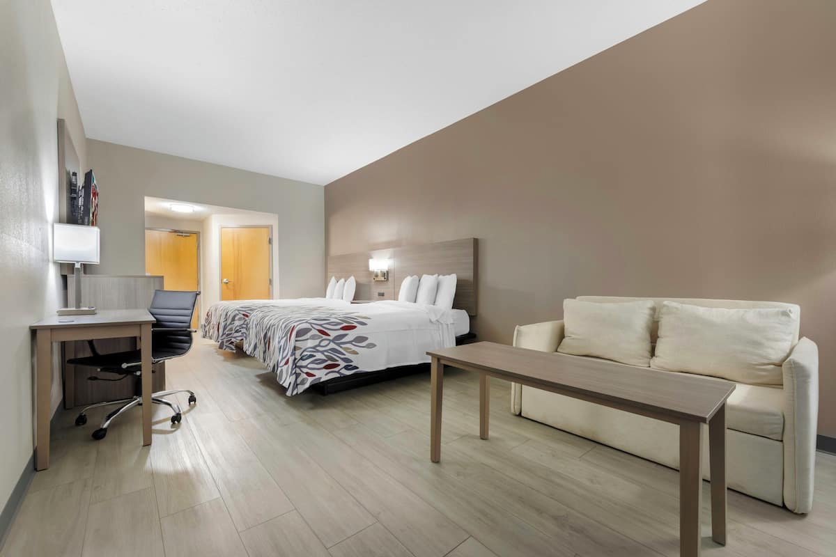 Une chambre d’hôtel comprenant un lit, un bureau, une chaise, un canapé et une table de chevet.