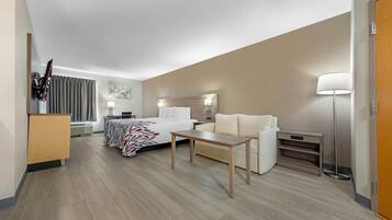 Une chambre d’hôtel comprenant un lit, un canapé, un bureau, une lampe, une télévision et une armoire.
