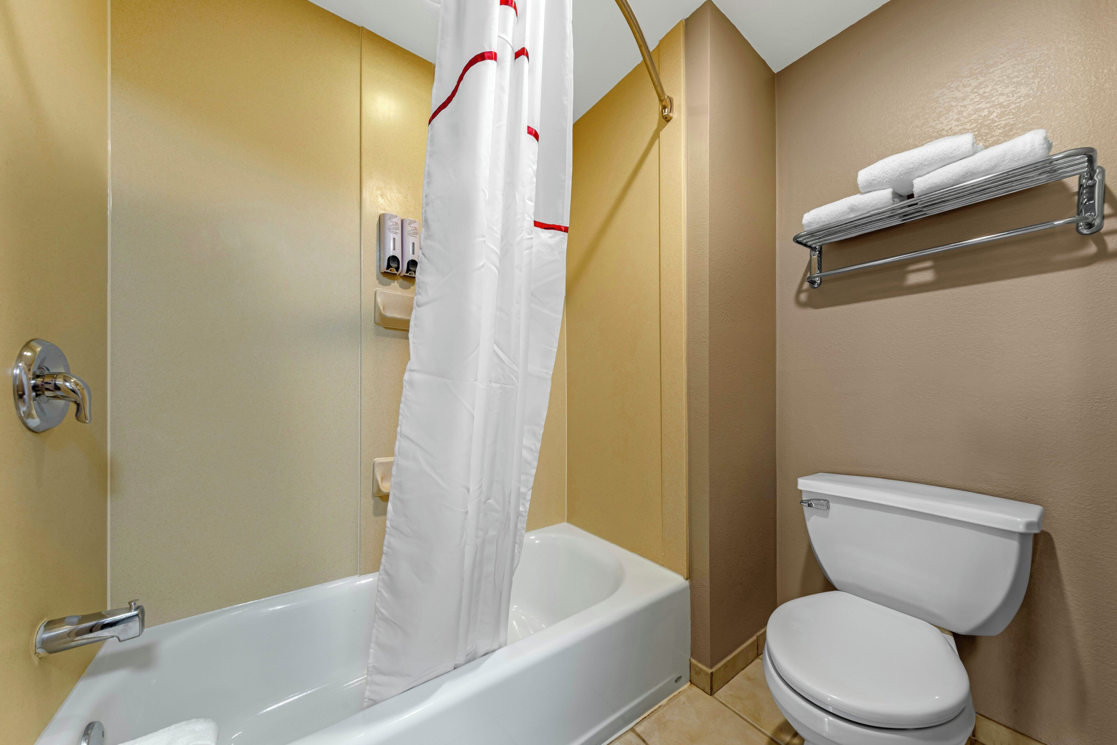 A bathroom with a bathtub, toilet, shower curtain, and a towel rack.