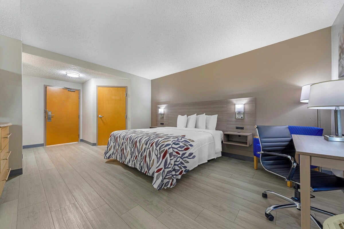 Une chambre d’hôtel équipée d’un lit, d’un bureau, d’une chaise et de deux portes.