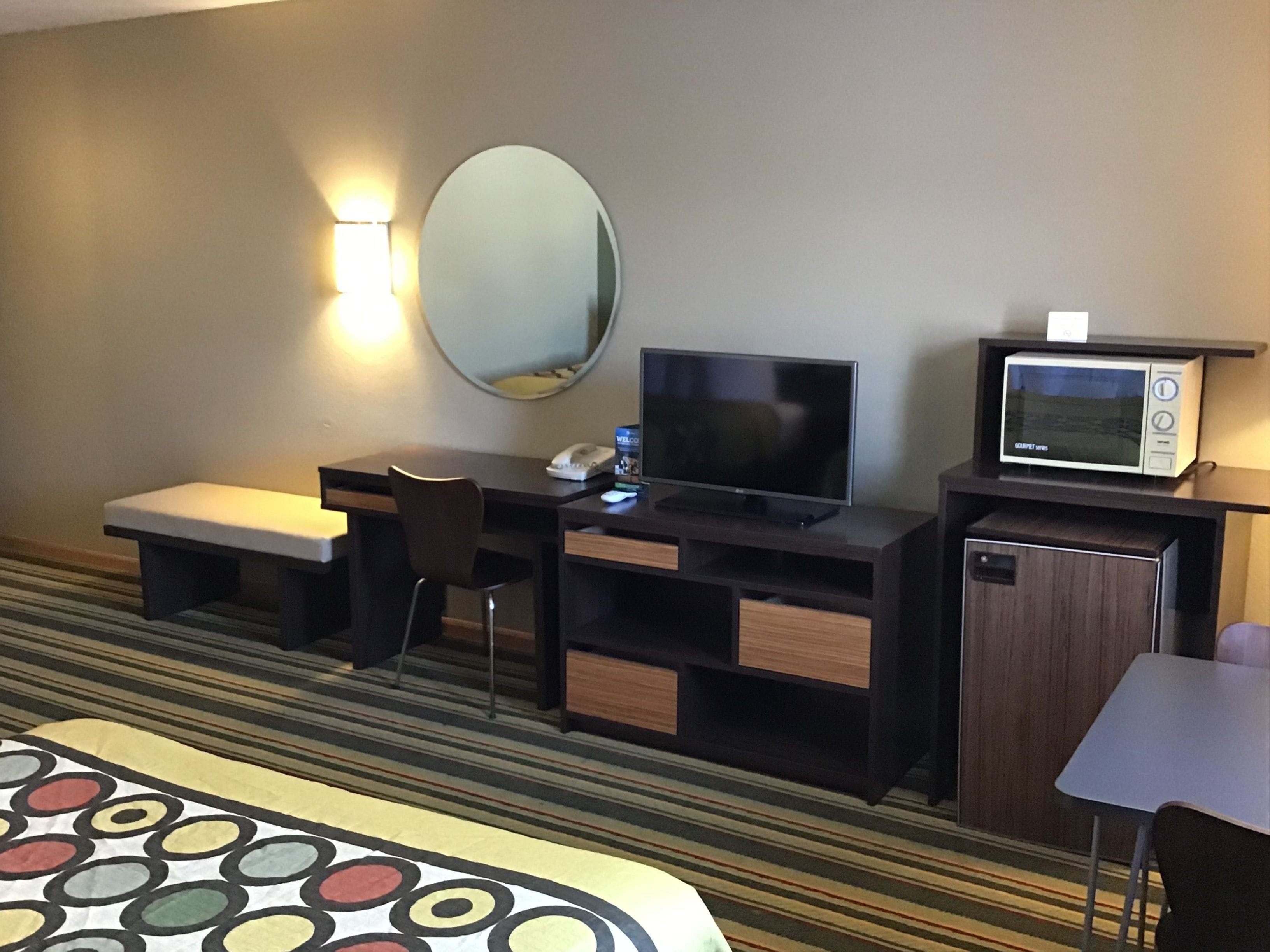 Hotelkamer met een bed, een bureau met een computer, een televisie, een magnetron en een kleine tafel.