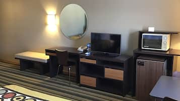 Hotelkamer met een bed, een bureau met een computer, een televisie, een magnetron en een kleine tafel.