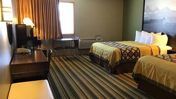 A hotel room with a bed, a desk, a chair, a telephone, and a window with curtains.