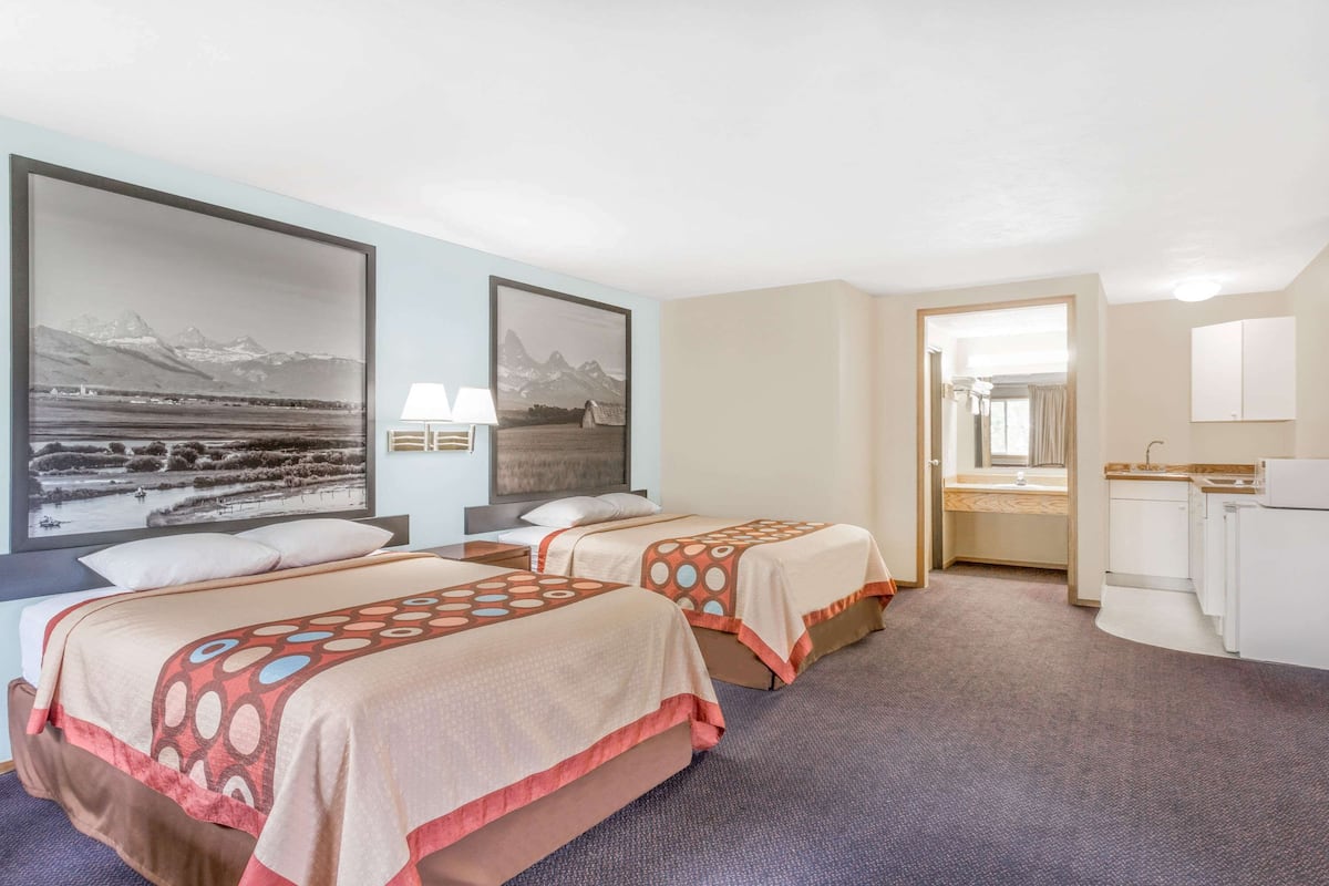 Een hotelkamer met twee bedden, een badkamer en uitzicht op bergen.
