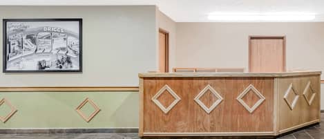 A reception area with a wooden reception desk, a framed welcome sign, and a patterned carpet.