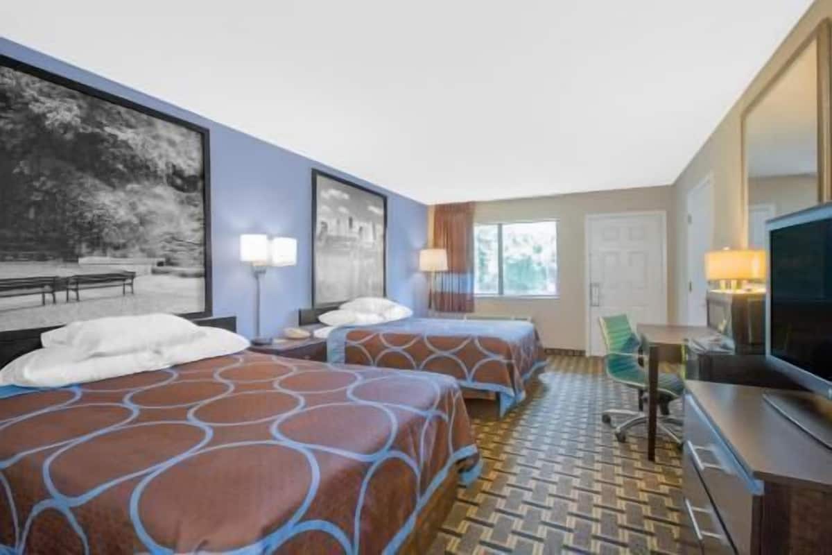 Een hotelkamer met twee bedden, een televisie, een bureau en een stoel.