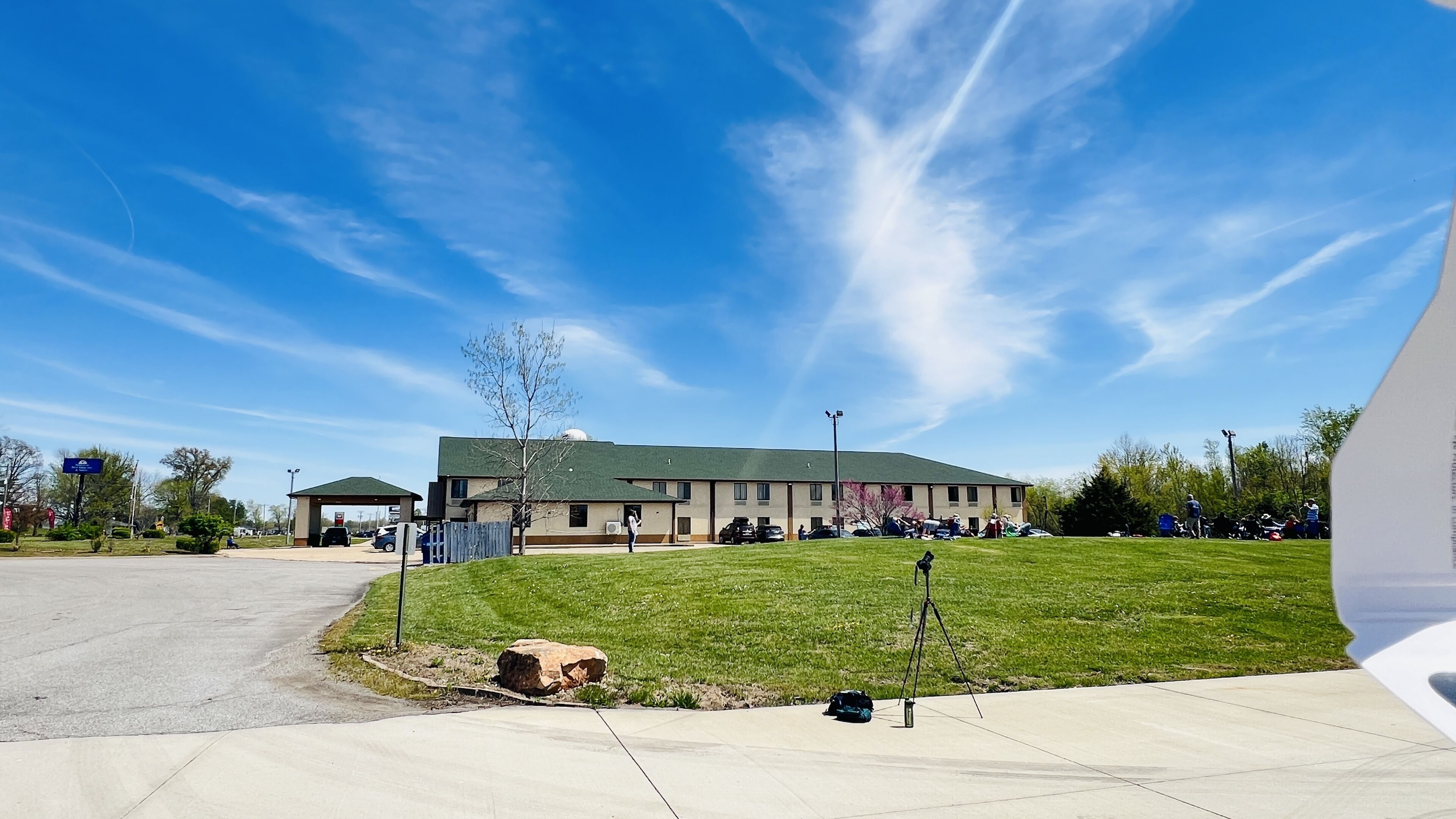 A building with a flat roof, a parking lot, and a grassy area in front.