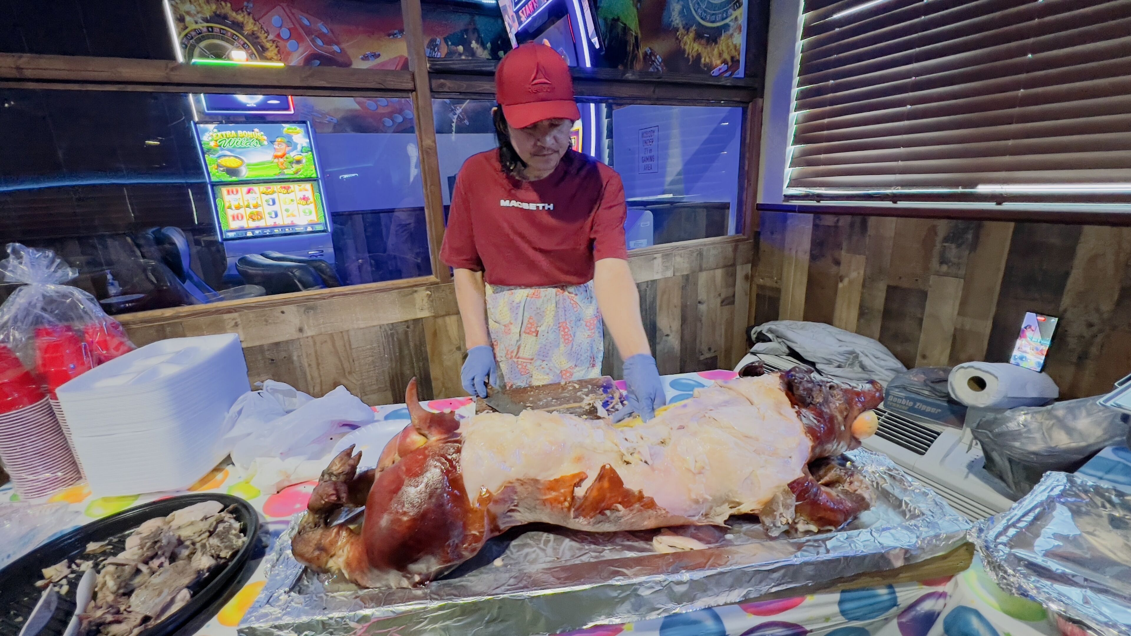 A person carving a large roasted pig on a table in a restaurant.