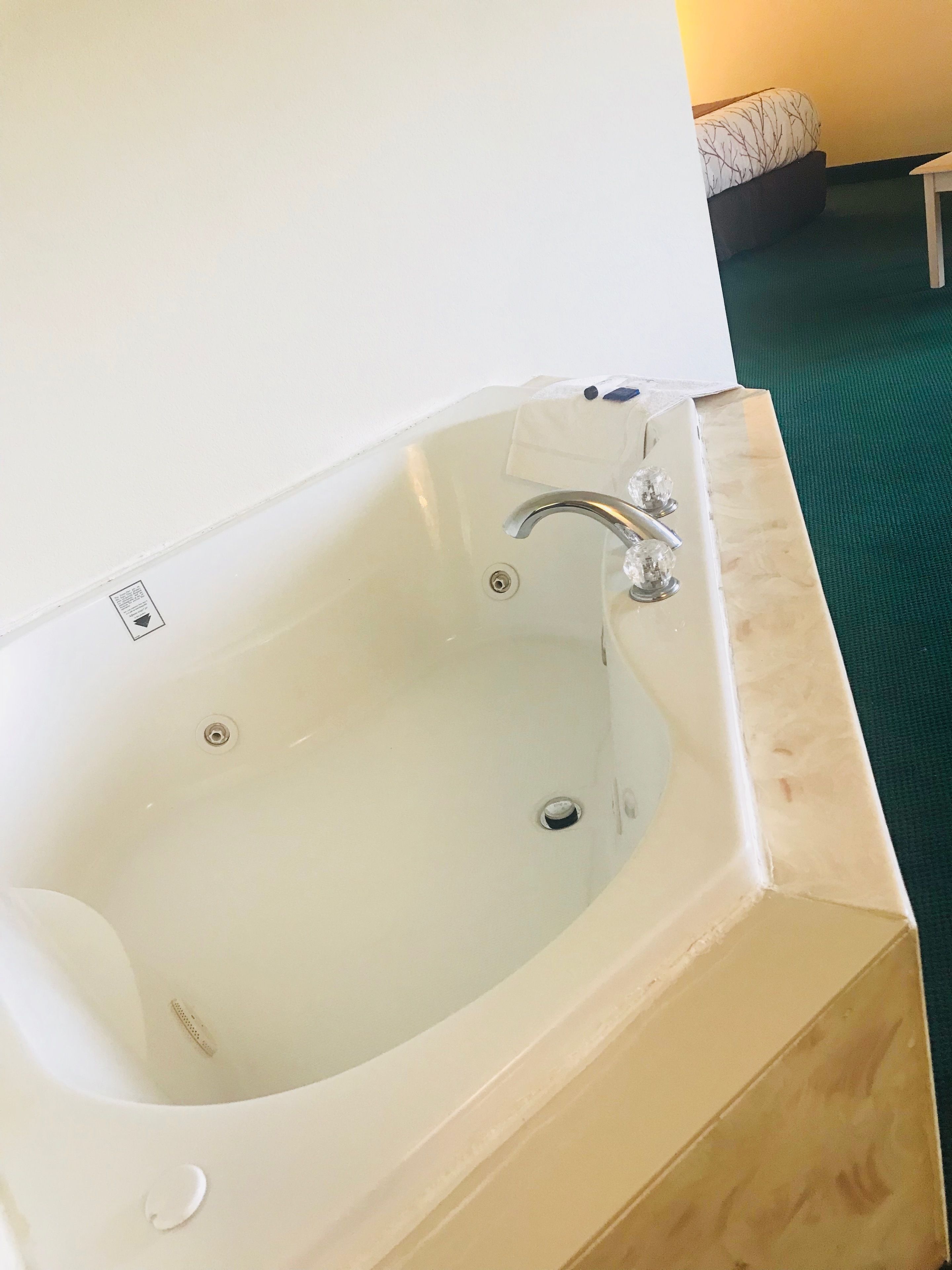 A modern bathroom with a large bathtub, a white sink, and a green carpeted floor.