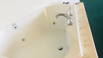 A modern bathroom with a large bathtub, a white sink, and a green carpeted floor.