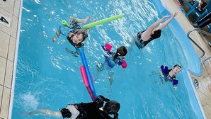 A swimming pool with multiple people engaged in water activities. -  Pinckeyville Inn and Suites (Pinckneyville)