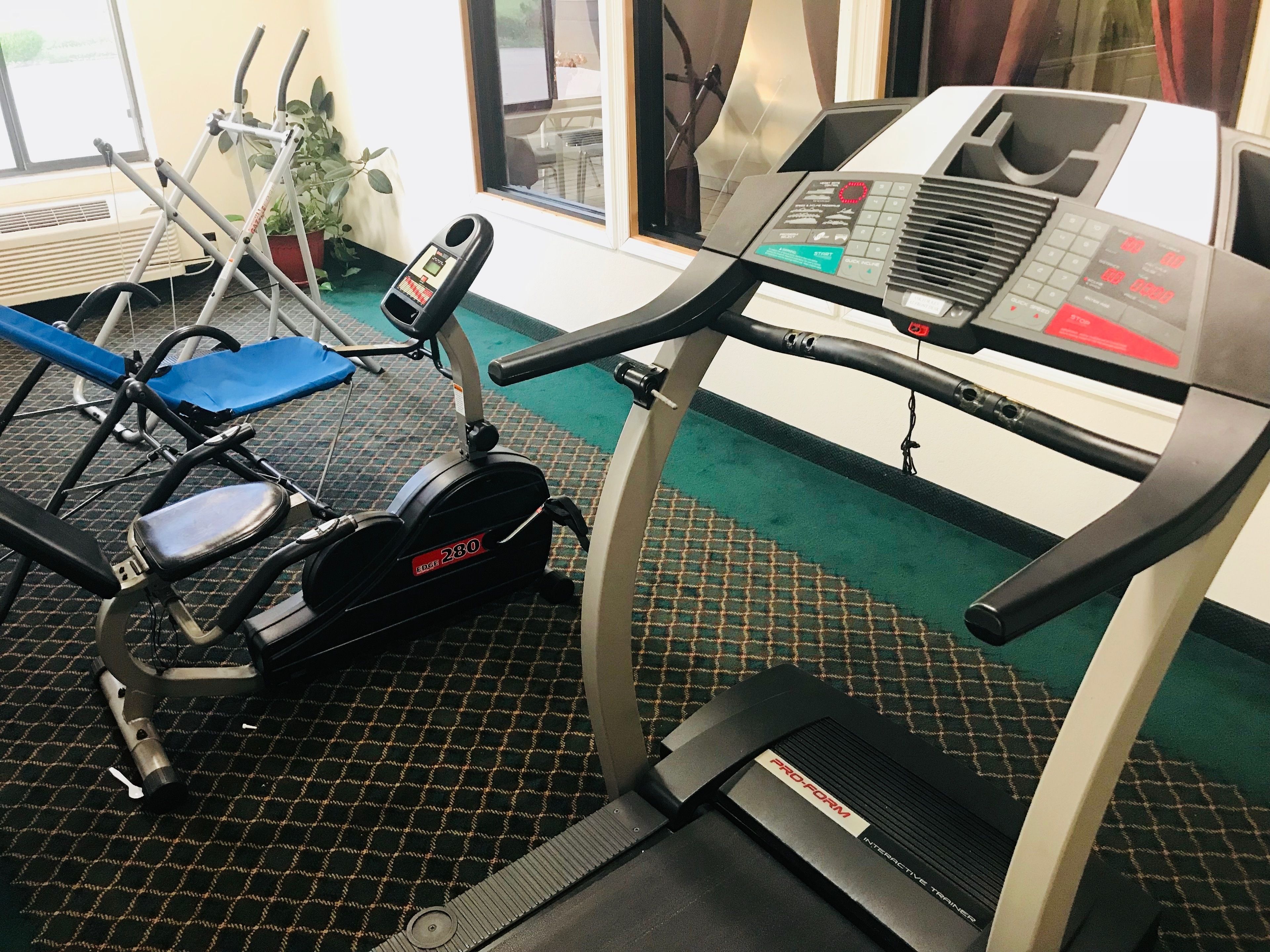 A gym with an elliptical trainer, a stationary bike, and a treadmill.