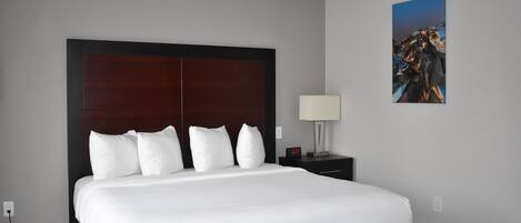 Una habitación de hotel con una cama grande, una mesita de noche con lámpara y un cuadro en la pared.