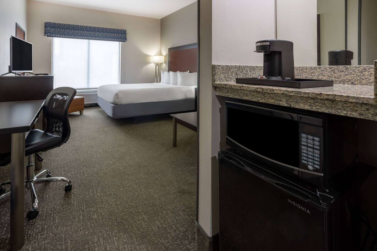 Une chambre d’hôtel équipée d’un lit, d’un bureau, d’une chaise et d’une machine à café.