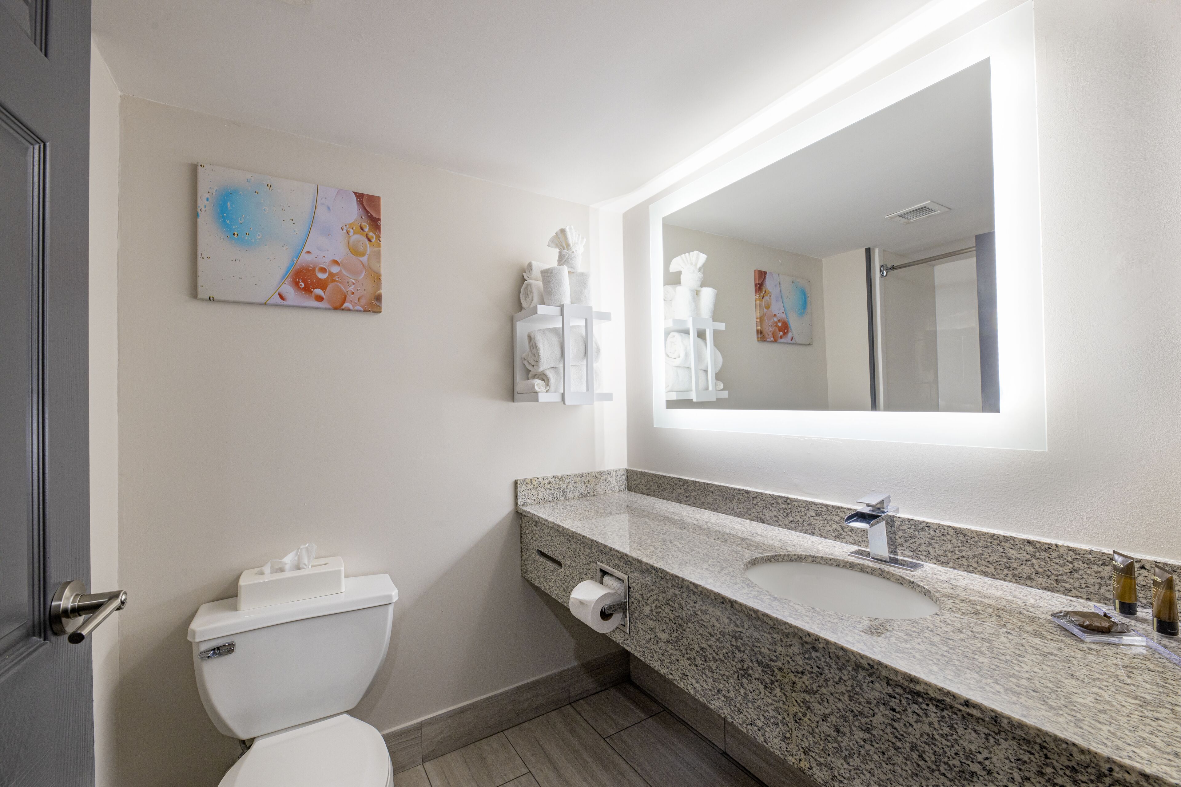 Een moderne badkamer met toilet, wastafel en grote spiegel.
