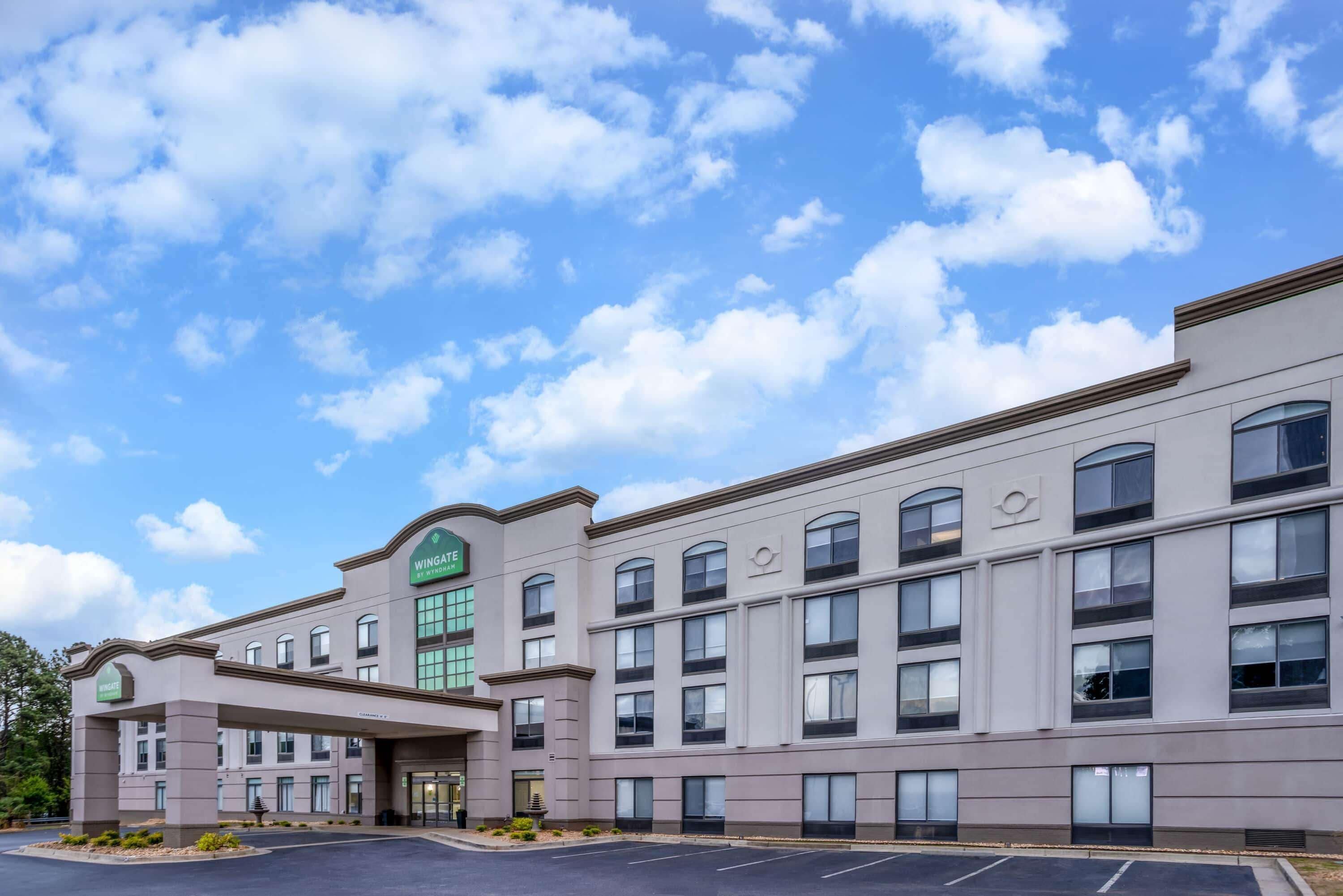 Un hotel con facciata moderna, numerose finestre e insegna verde con il nome.