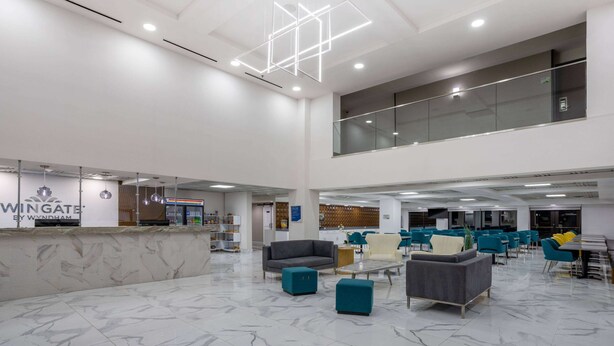 A spacious lobby with a marble floor, seating areas, a reception desk, and a glass railing overlooking the interior.