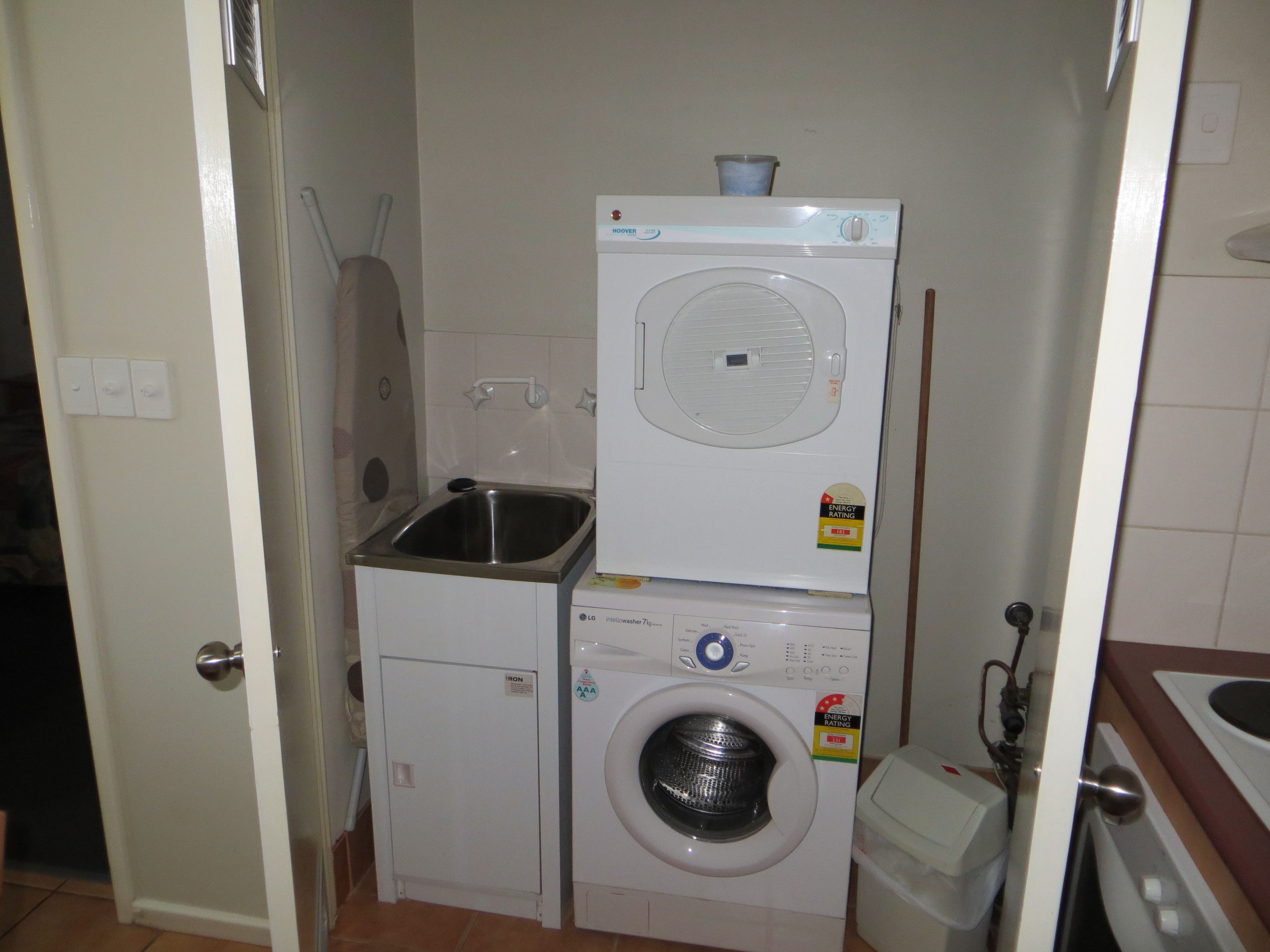A compact laundry area with a washing machine, a dryer, and a sink.