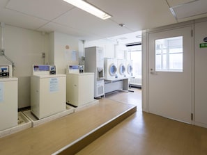 Un cuarto de lavandería con lavadoras, secadoras y un panel de control.
