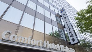 A modern hotel building with large glass windows and a prominent sign reading "Comfort Hotel."